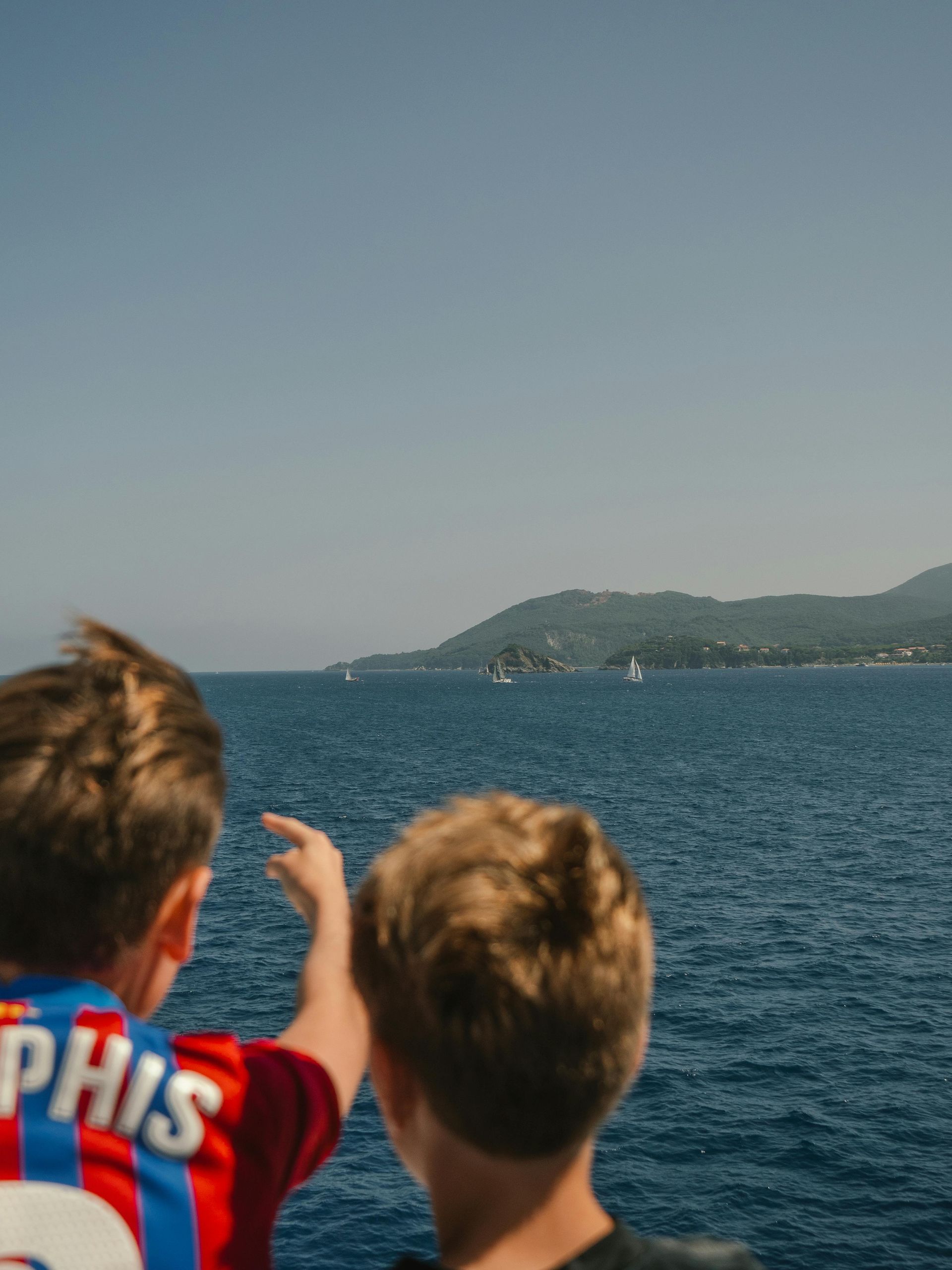 A man is holding an umbrella over a piggy bank and stacks of coins.