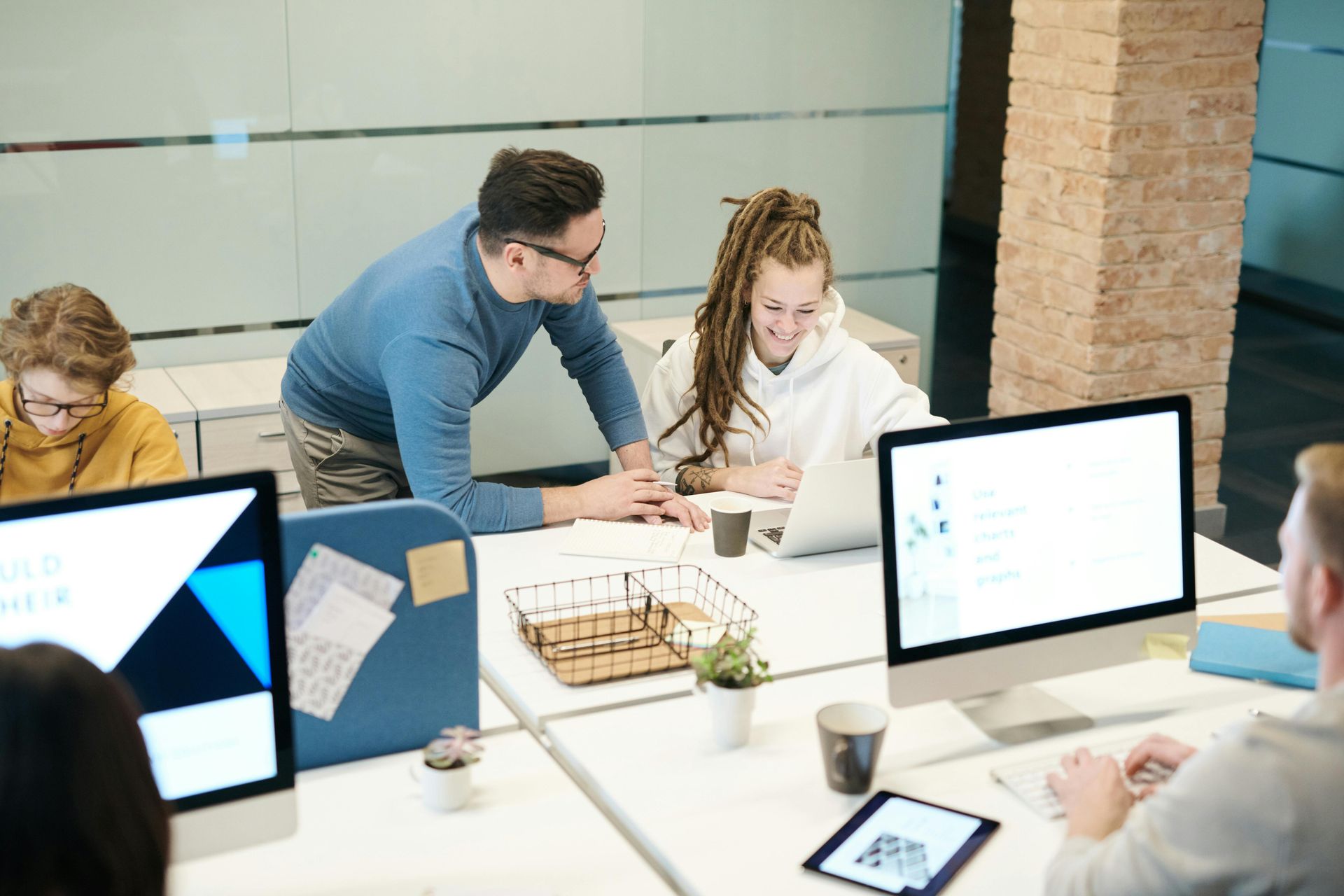 A group of people are sitting around a table with a laptop.