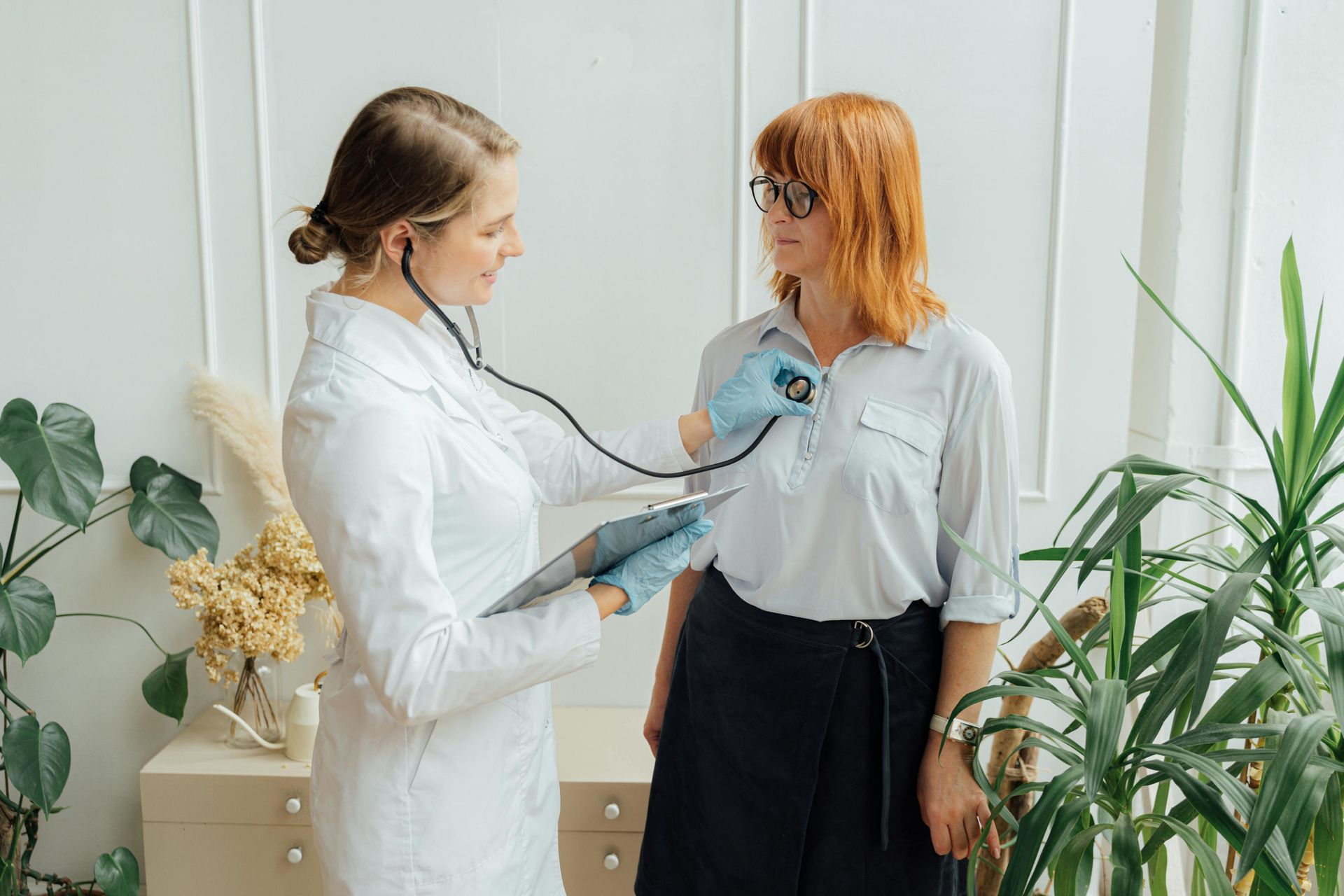 A doctor is listening to a patient 's heart with a stethoscope.