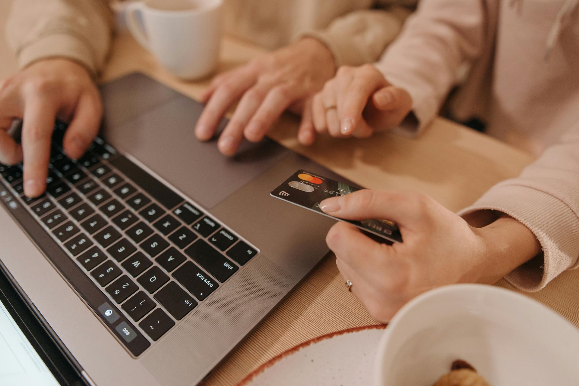 A group of young people are standing around a table looking at a laptop.
