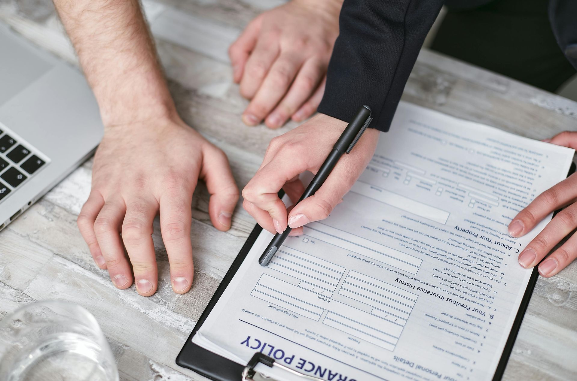 A man and a woman are signing a insurance policy on a clipboard.