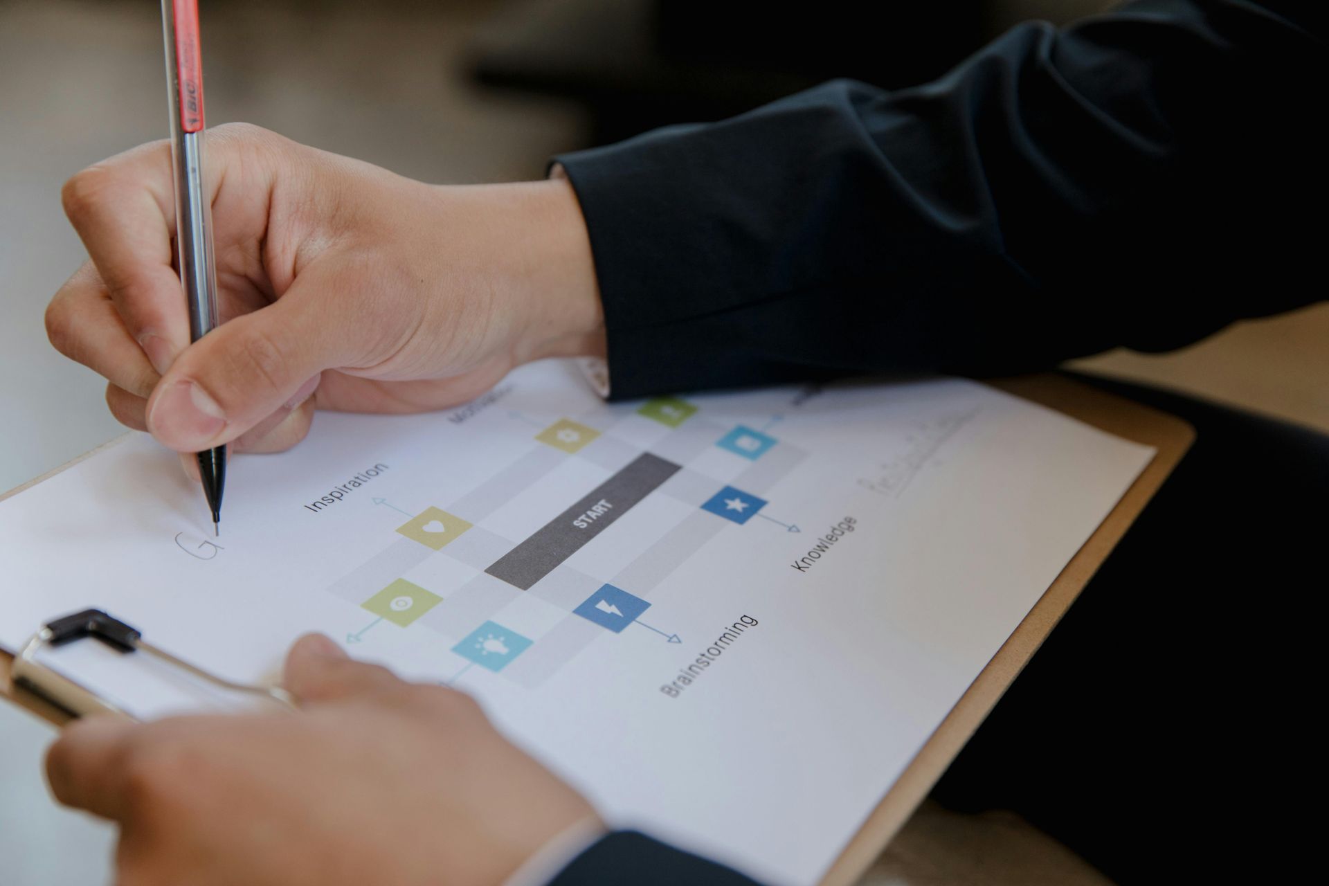 A man and a woman are sitting at a table looking at a laptop.