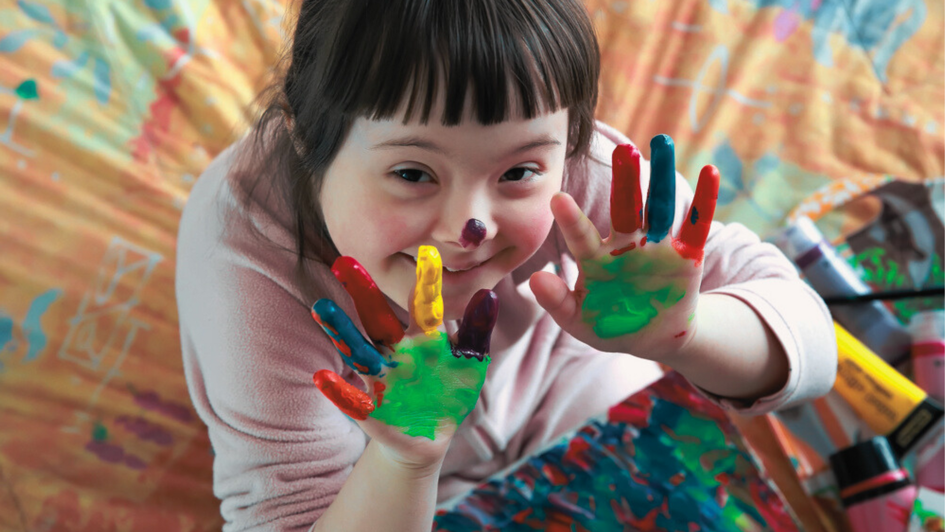 Art therapy session with a young resident at Hope House smiling with painted fingers