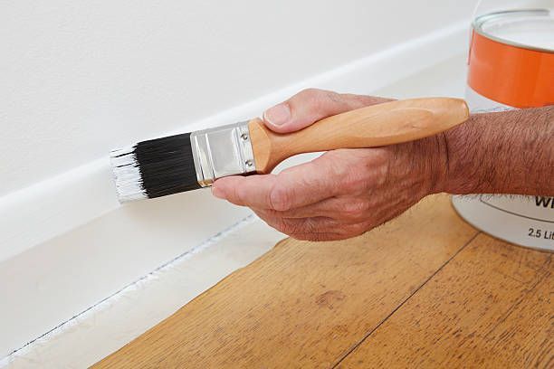 A person is painting a wall with a brush.