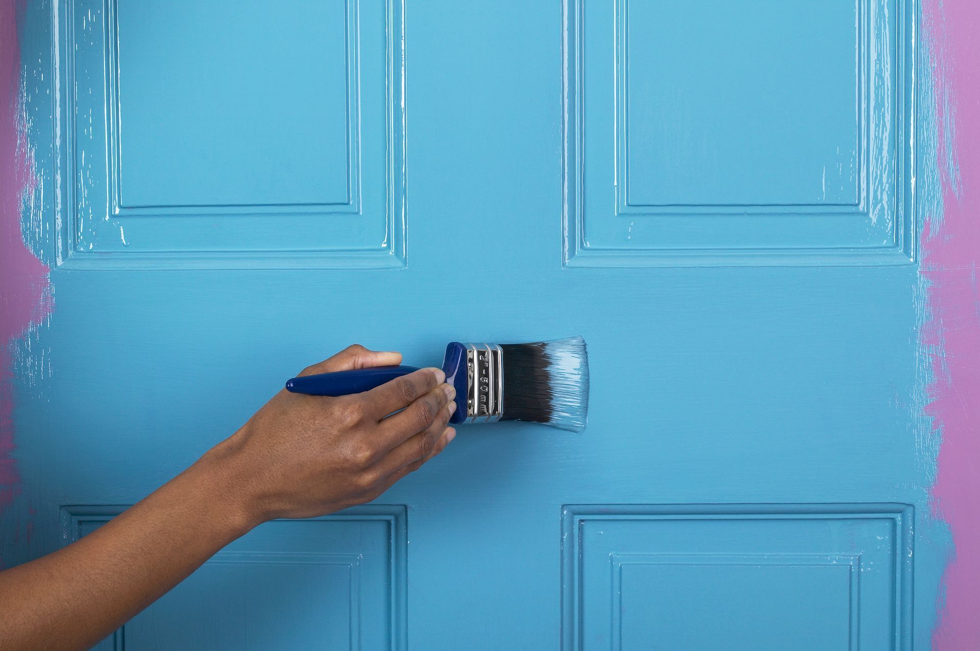 A person is painting a blue door with a brush.
