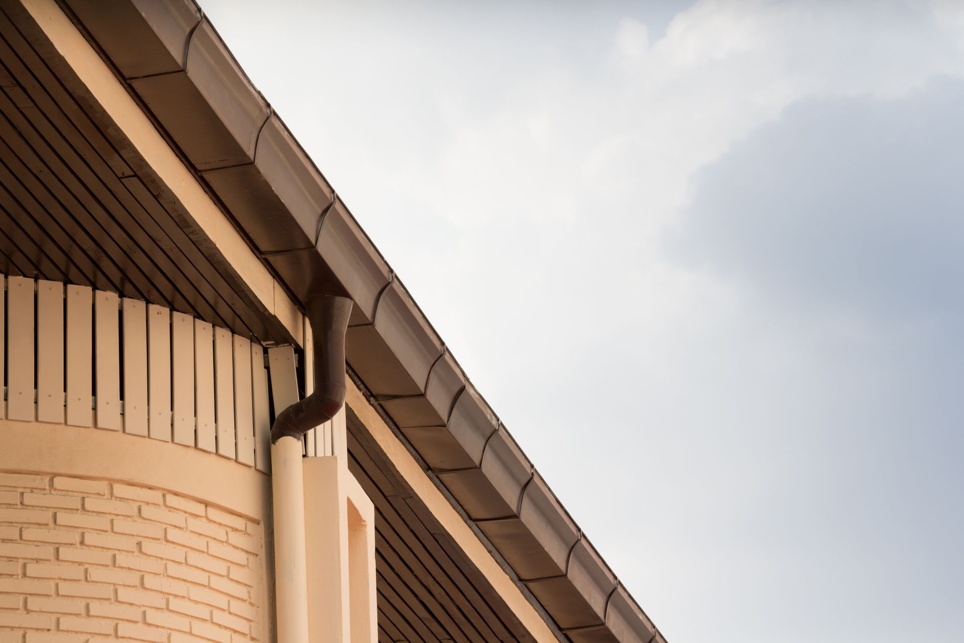 A brick building with a brown gutter on the roof.