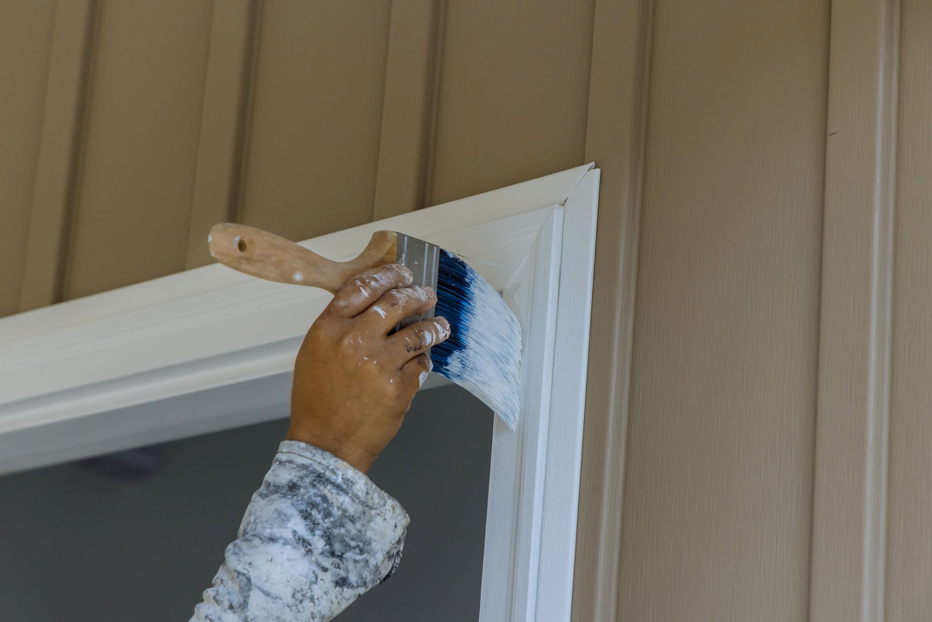 A person is painting a door frame with a brush.