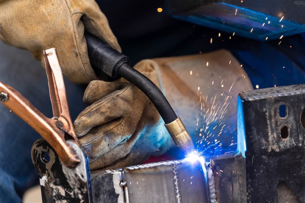Man Is Welding A Piece Of Metal With A Welding Torch — Aliweld Fabrications In Caloundra West, QLD