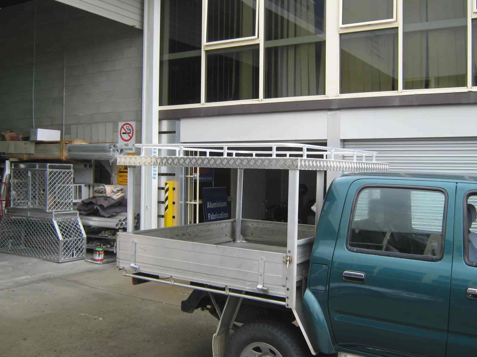 A Green Truck With an Open Cargo Tray is Parked Outside a Building — Aliweld Fabrications In Sunshine Coast, QLD