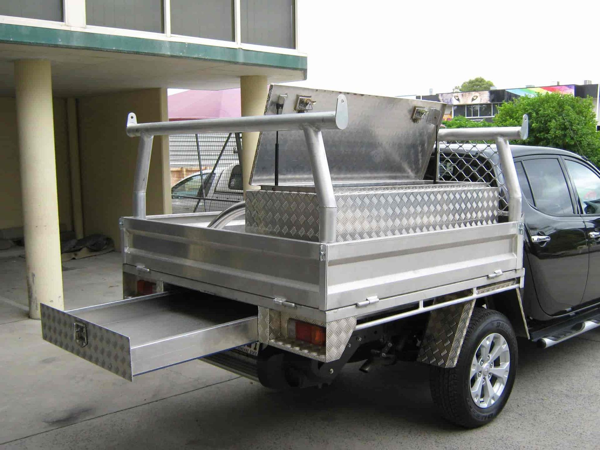 A Truck With a Tray on the Back is Parked in Front of a Building — Aliweld Fabrications In Caloundra West, QLD