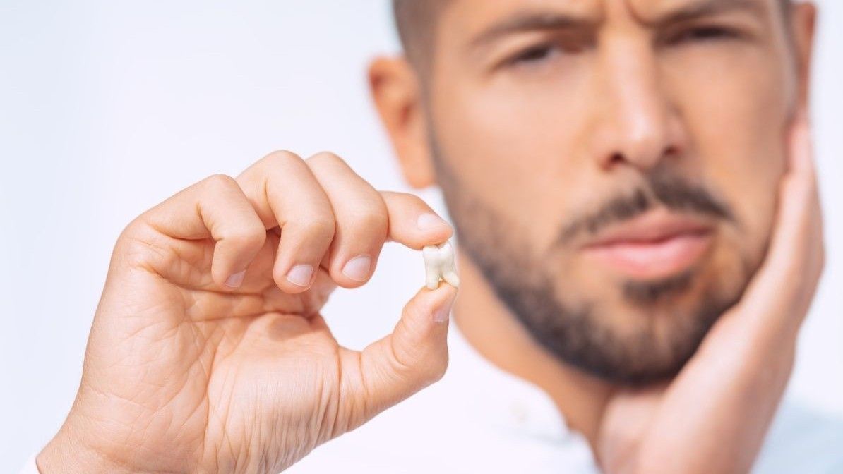 A patient holds his extracted tooth