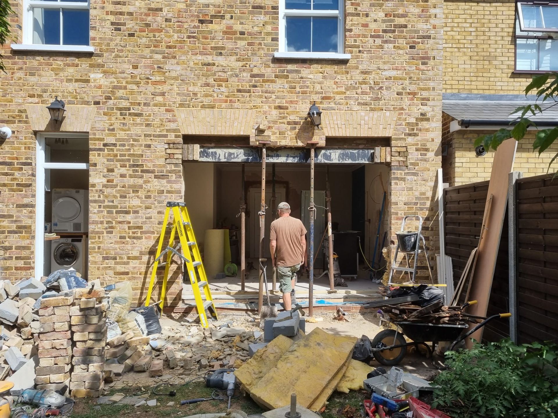 A man is standing in front of a brick building under construction.