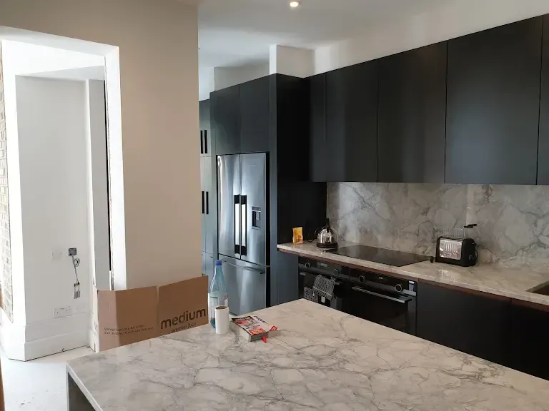 A kitchen with black cabinets and a marble counter top