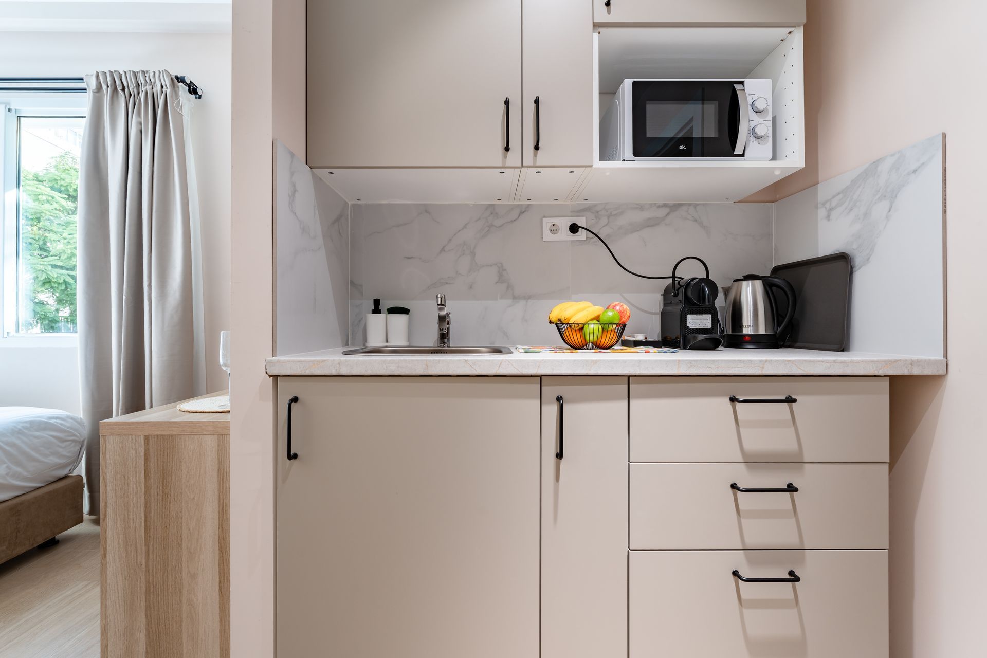 Pequeña cocina equipada con armarios, electrodomésticos, fregadero y frutero.