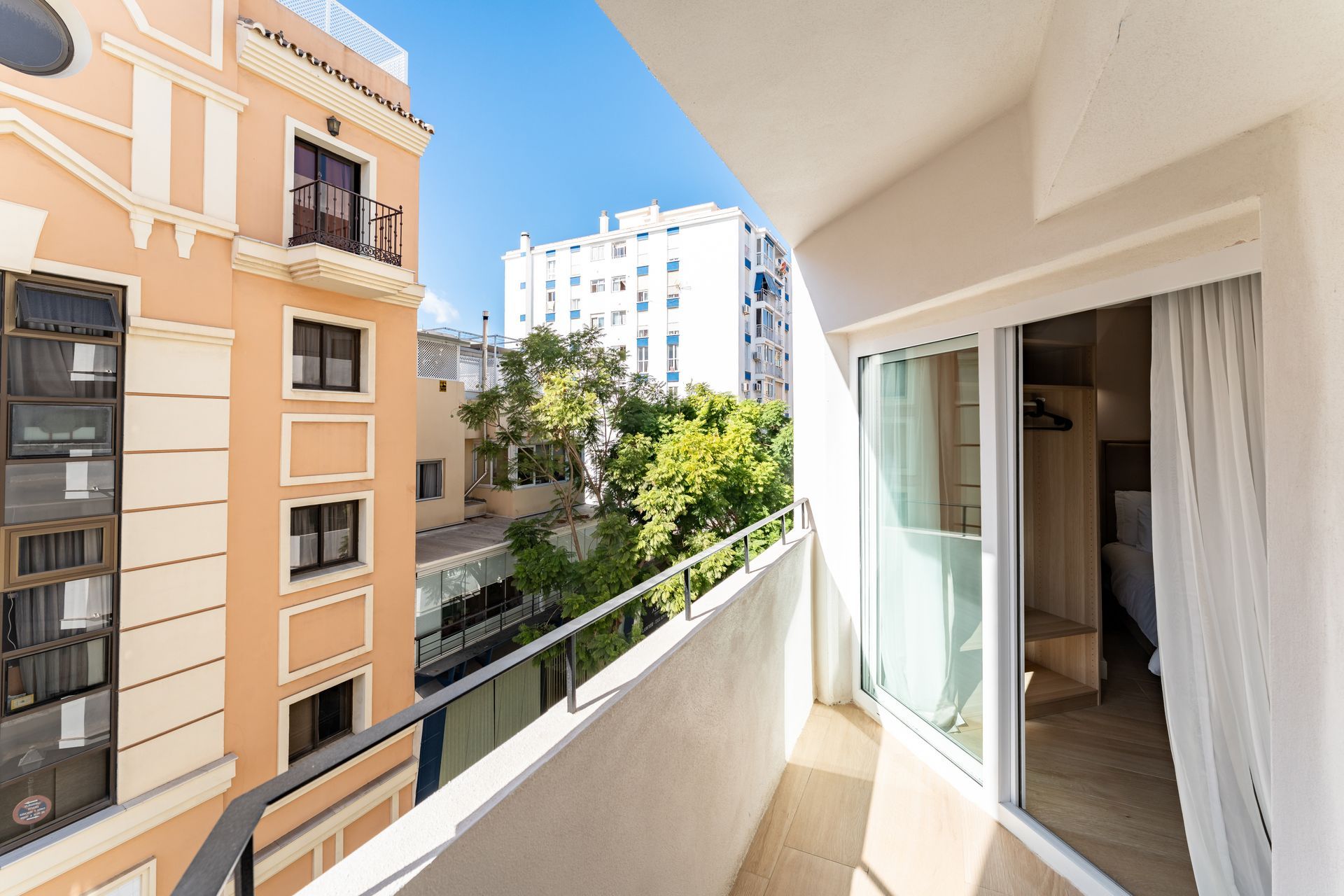 Vista desde el balcón de edificios y árboles en un día soleado.