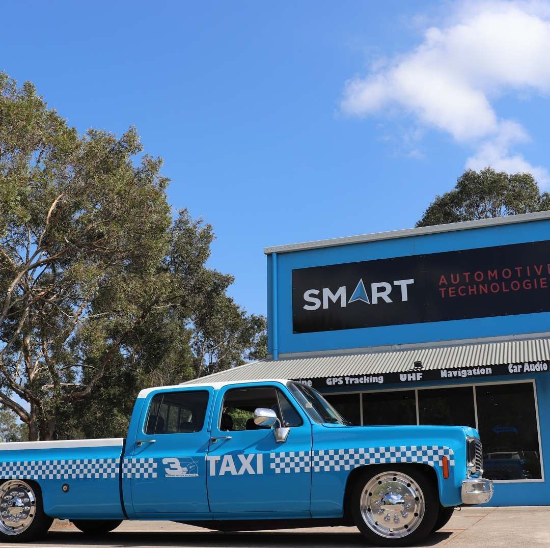 A Blue Taxi Truck is Parked in Front of a Building — Smart Automotive Technologies in Noosaville, QLD