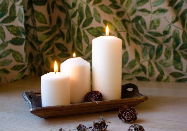 Three white pillar candles glow softly on a rustic tray with cremation services in Marrero, LA