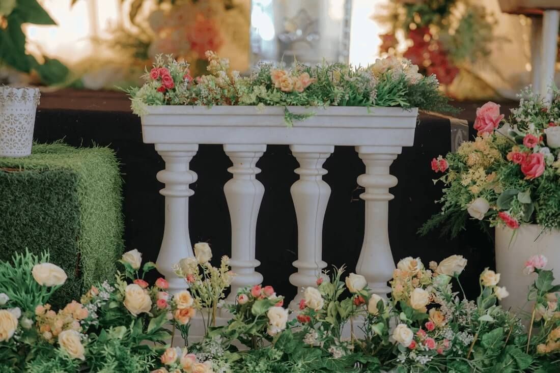 White decorative stand surrounded by lush pastel flowers with cremation services in New Orleans, LA