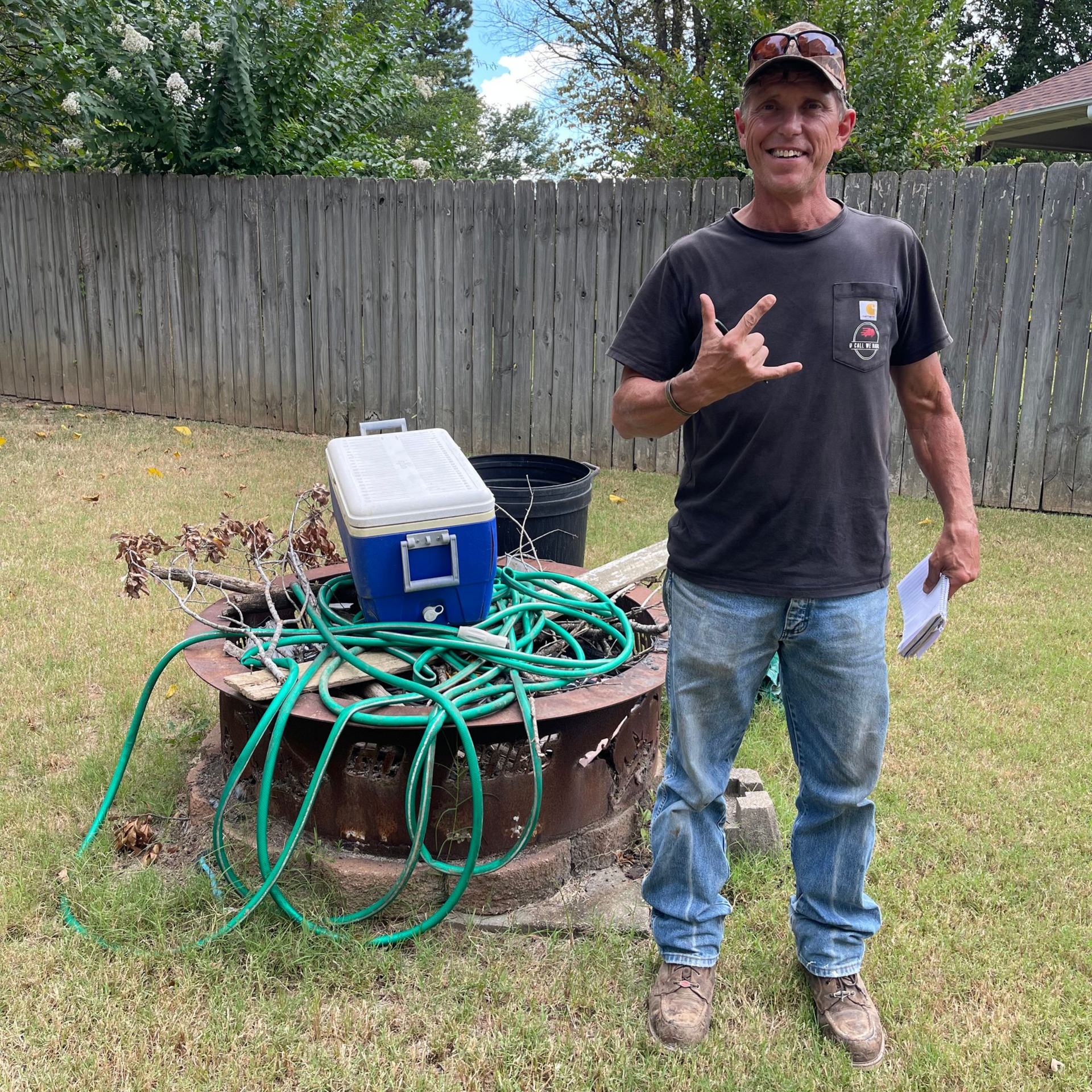 Man loading a trailer with junk, wearing a cap and a shirt that reads 