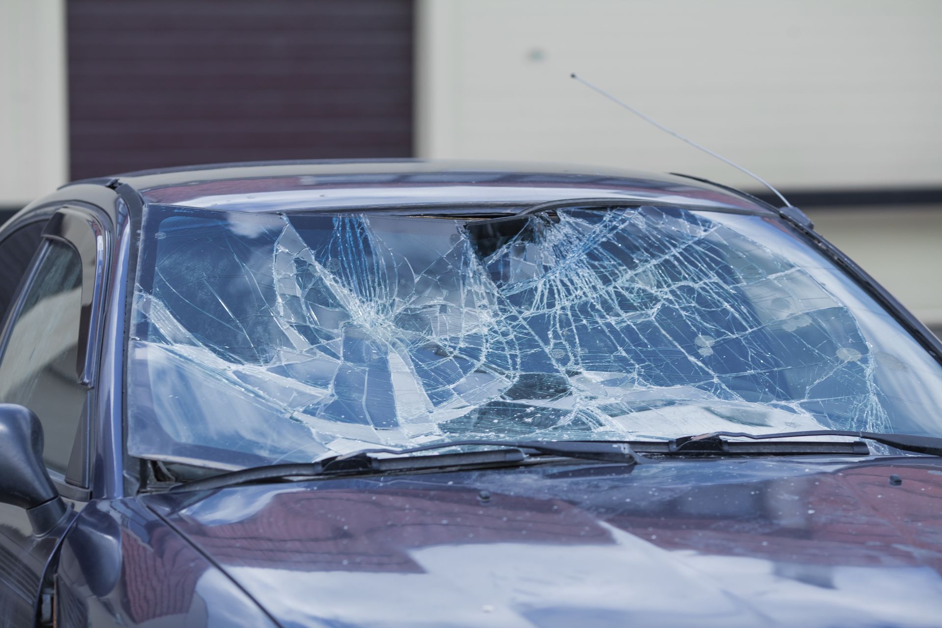 AutoPage & Glass | Milwaukee | Auto Glass Replace A car with a broken windshield is parked in front of a building.
