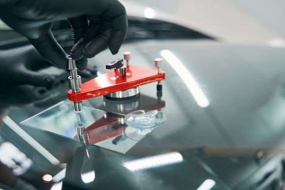 Autopage & Glass A person is repairing a cracked windshield on a car.