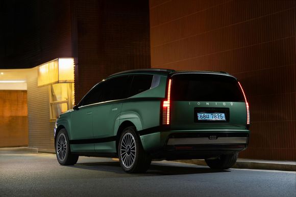 Green SUV parked at night with vertical taillights.