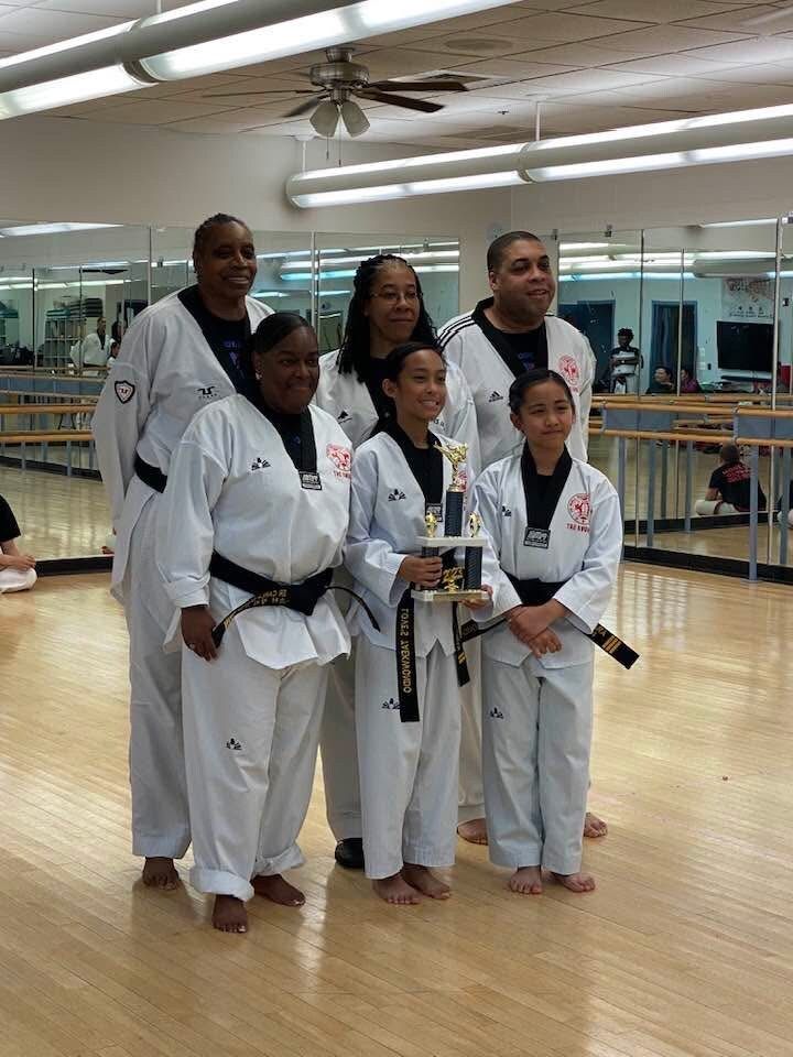 A group of people in karate uniforms are posing for a picture in a gym.
