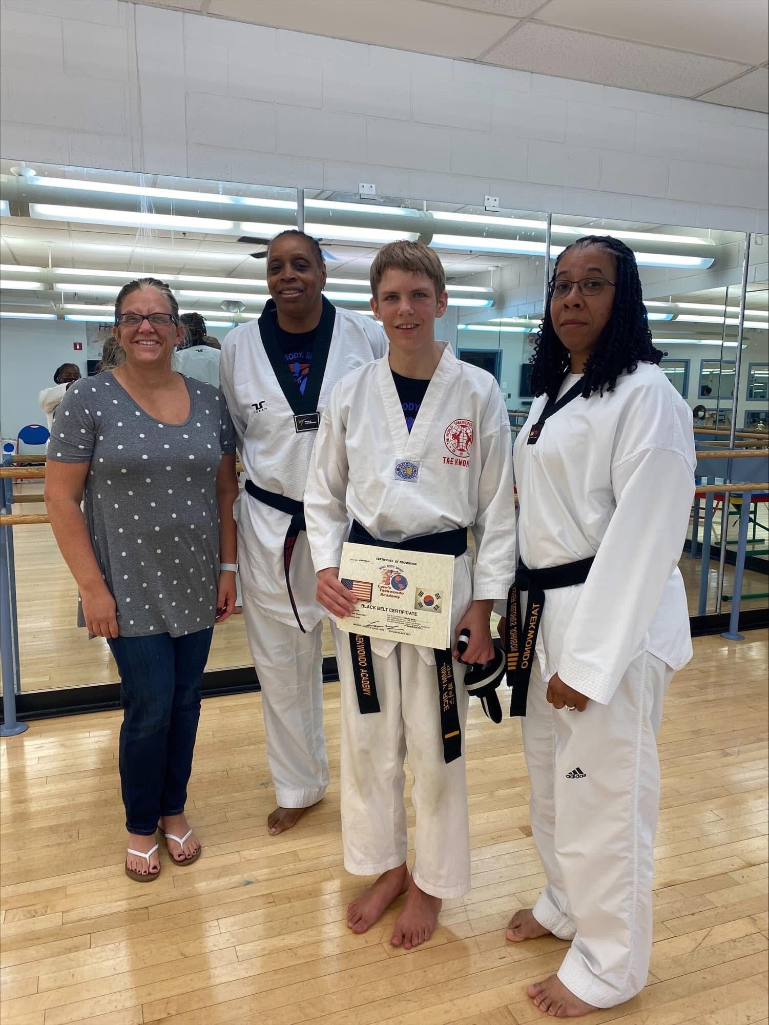 A group of people in karate uniforms are posing for a picture in a gym.