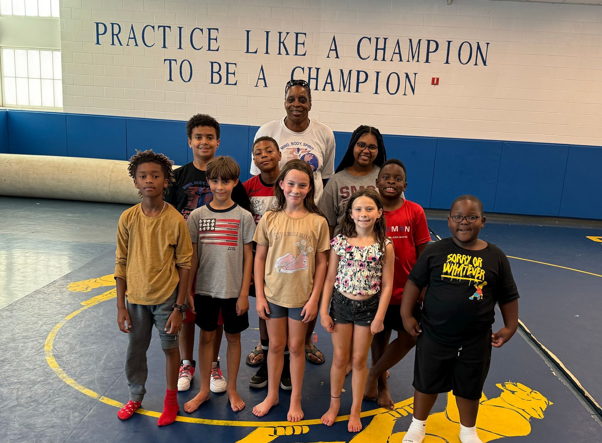 A group of children standing in front of a wall that says practice like a champion to be a champion