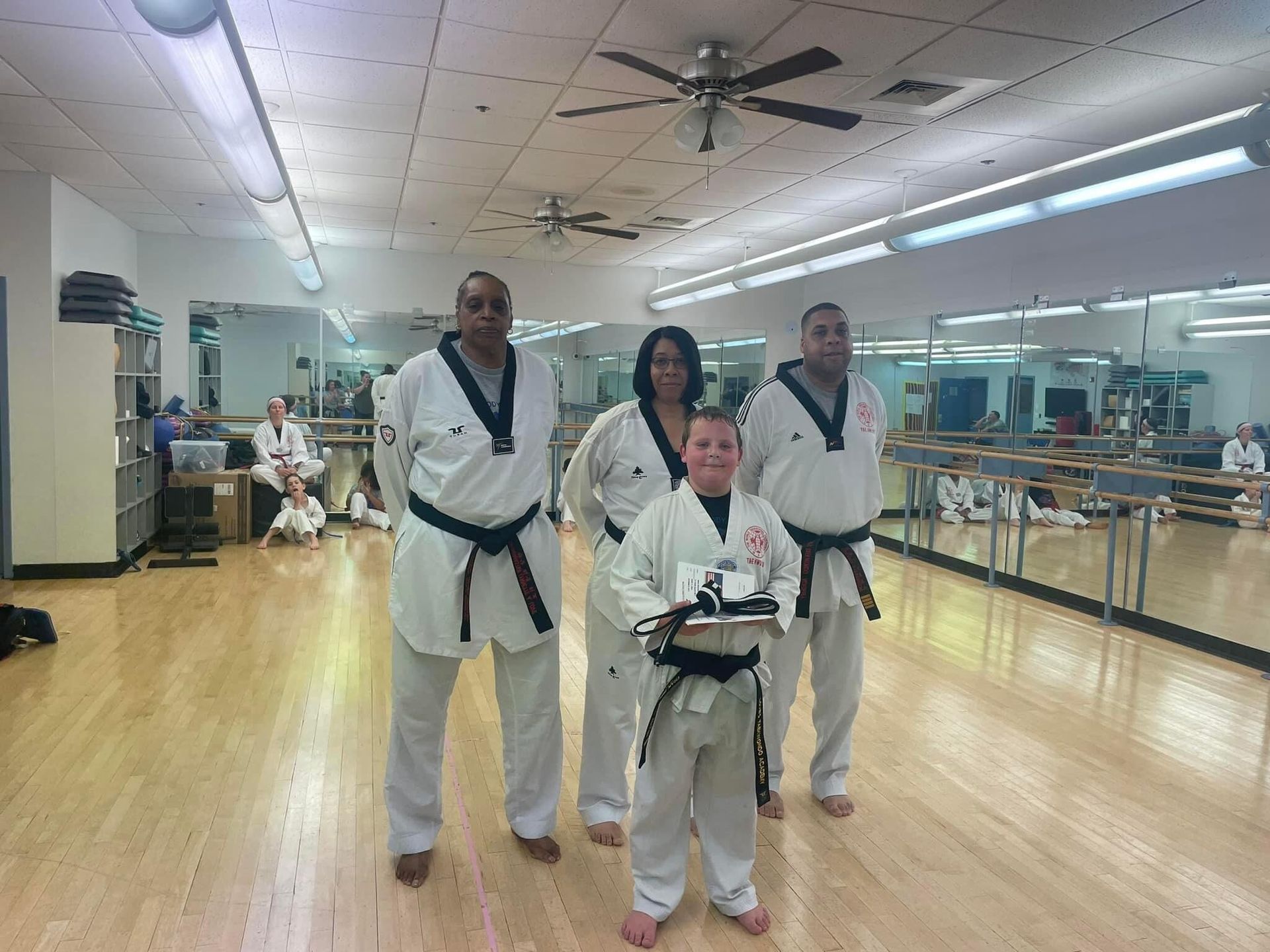 A group of people in karate uniforms are posing for a picture in a gym.