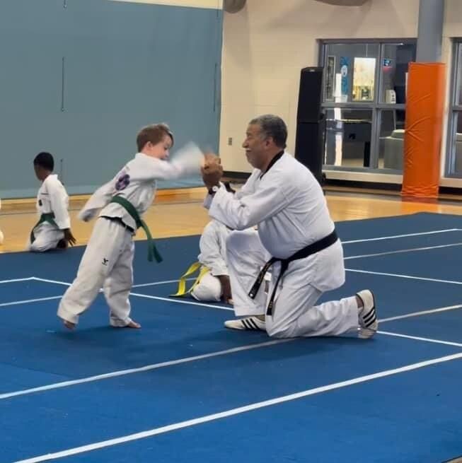 A man kneeling down with a child in a karate class