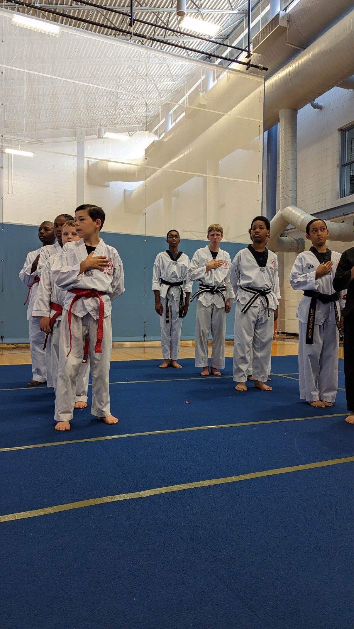 A group of people in karate uniforms are standing in a gym.