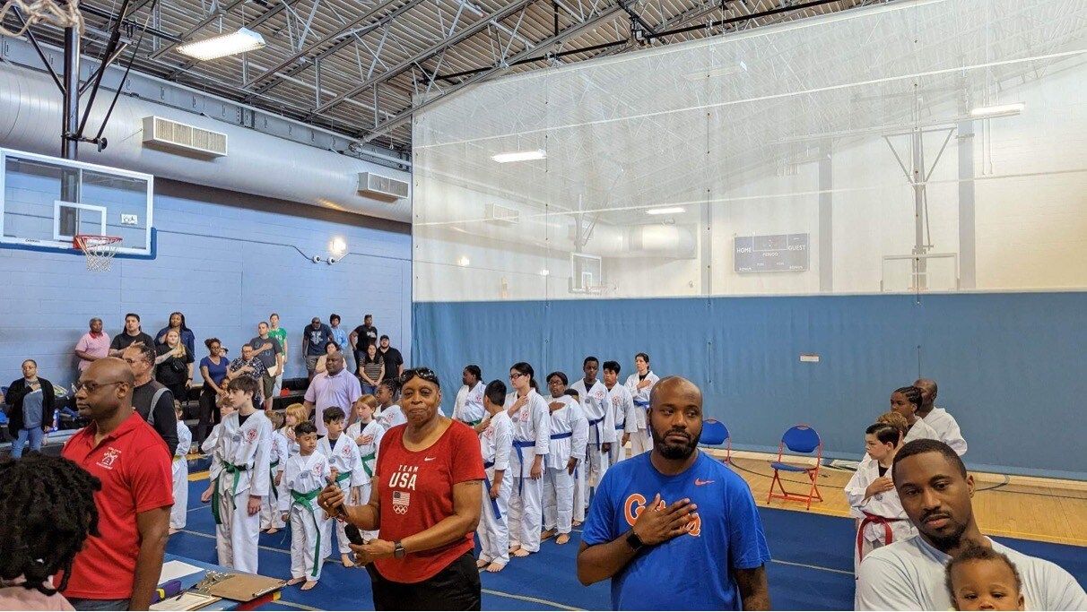A group of people are standing in a gym.