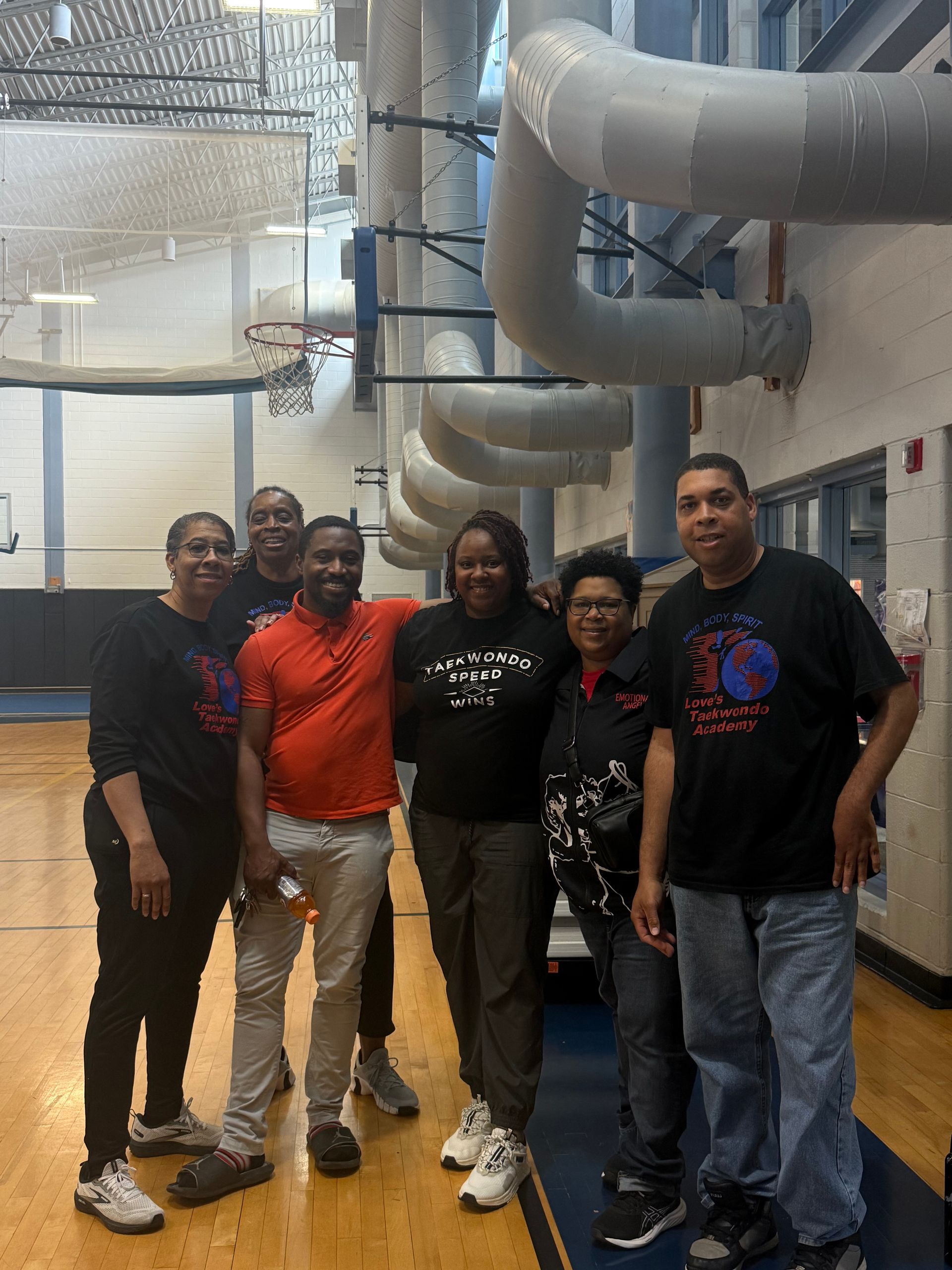 A group of people are posing for a picture in a gym.
