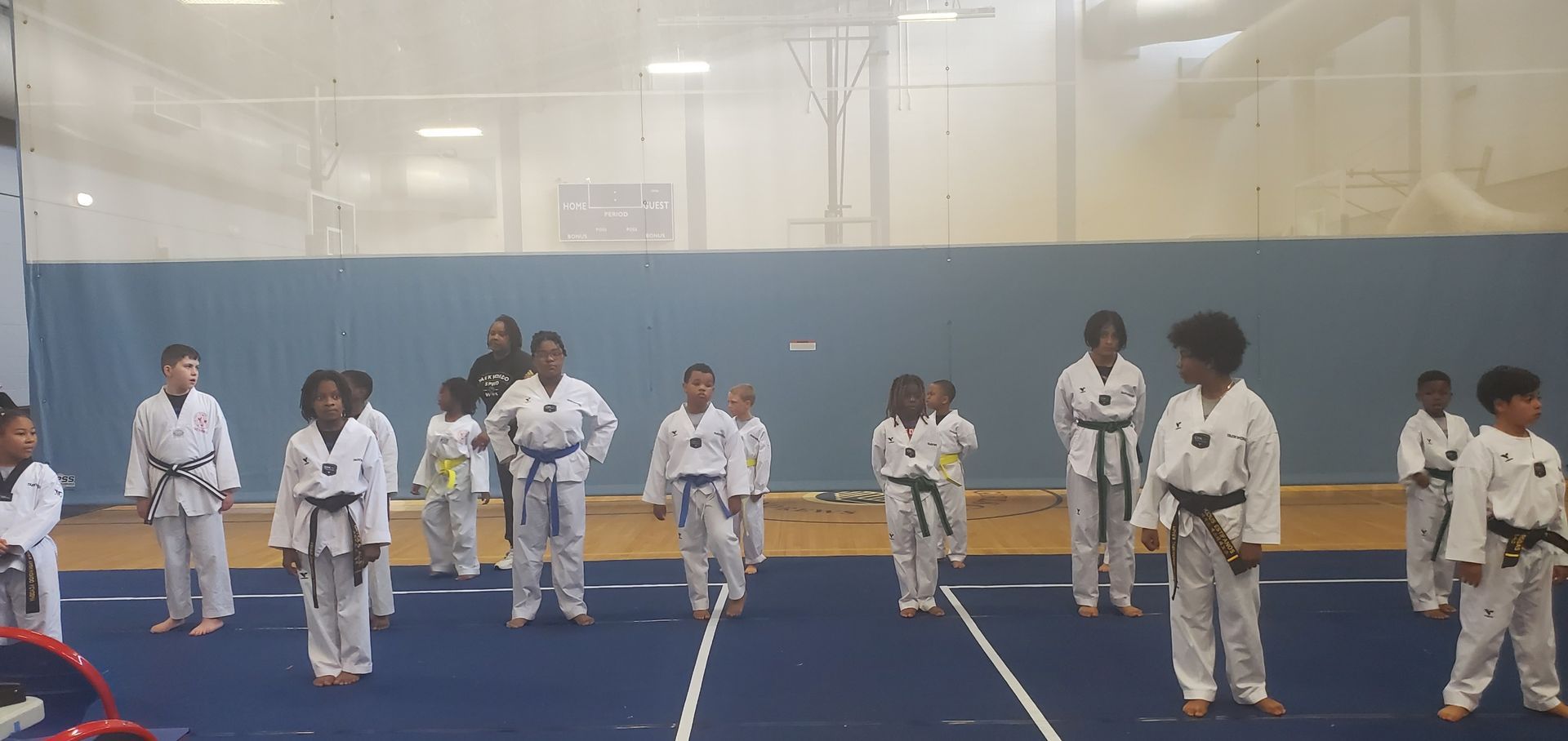 A group of children are practicing martial arts in a gym.