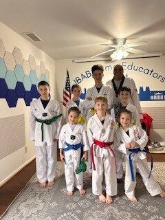 A group of children in karate uniforms are posing for a picture in a room.