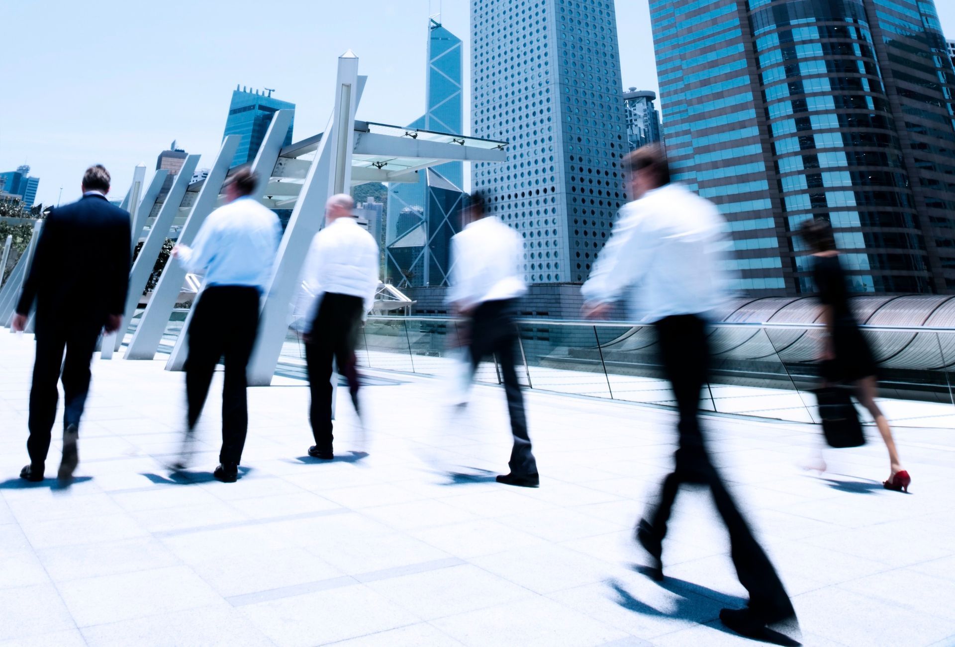 A group of business people are walking in front of a city skyline.