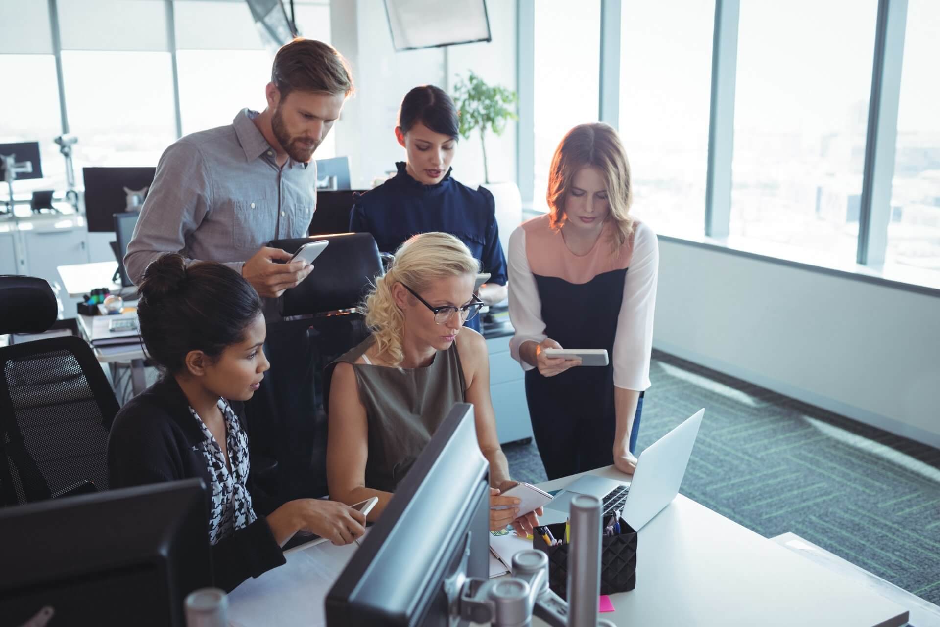 A group of people are looking at a computer screen in an office.