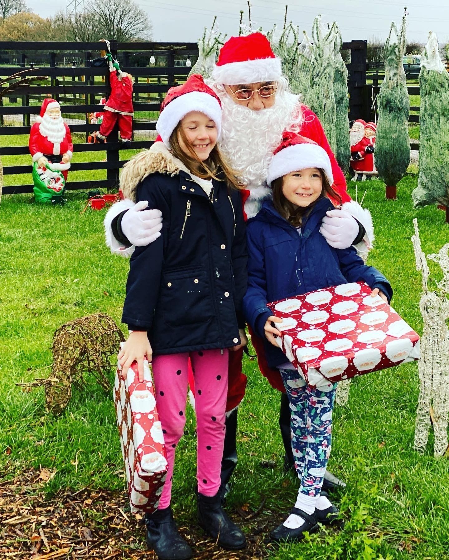 Two little girls are posing for a picture with santa claus