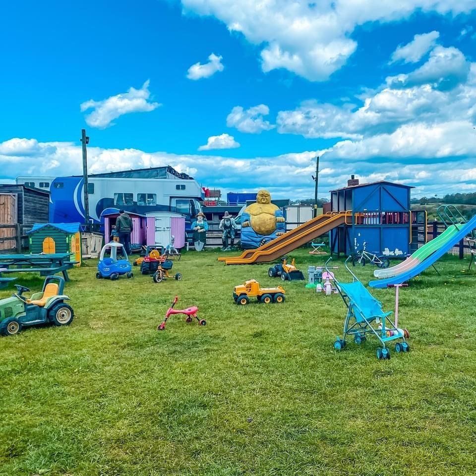 A field filled with lots of children 's toys and a slide.