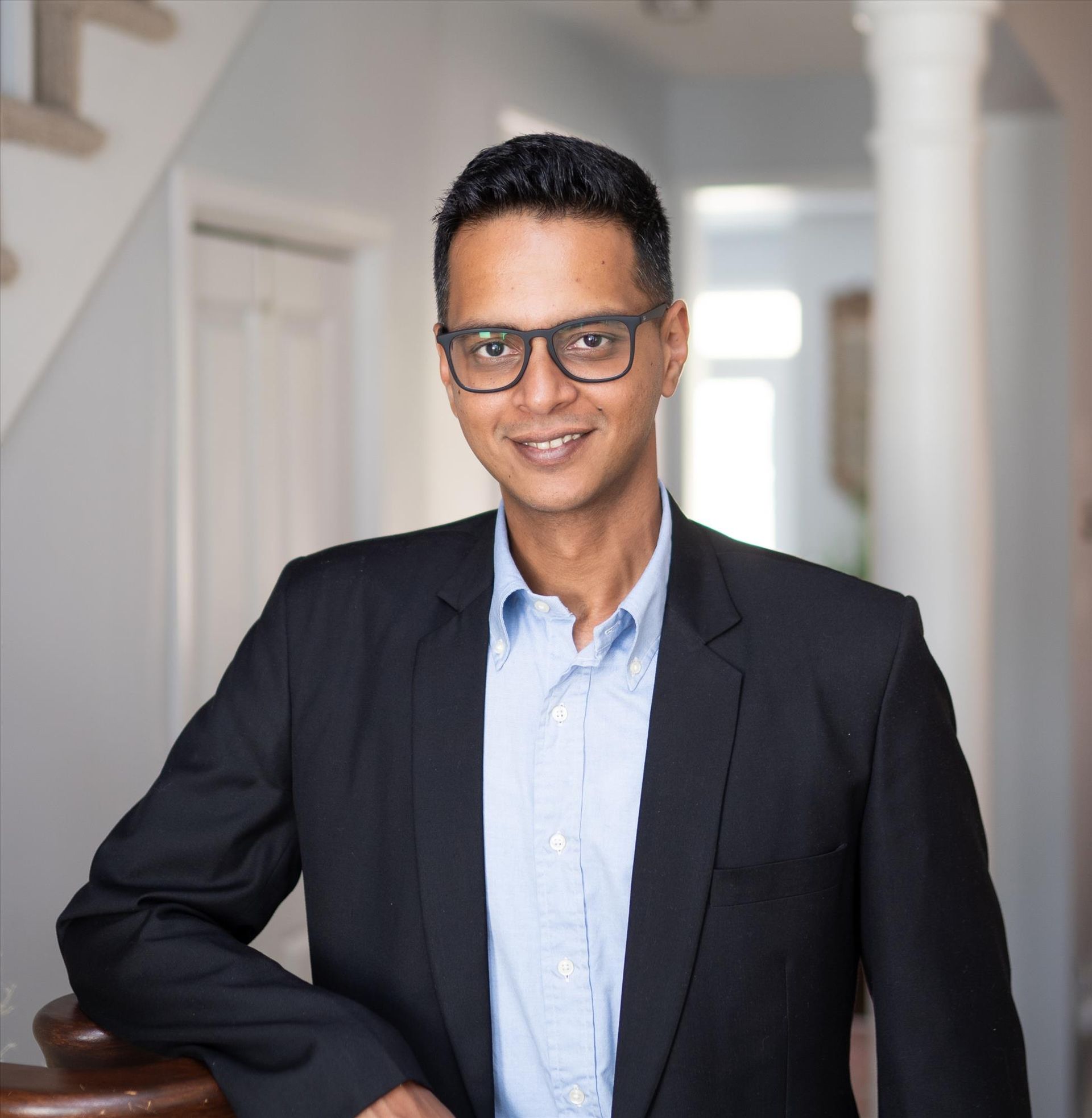 A woman is sitting at a desk with a laptop and a vase of flowers.