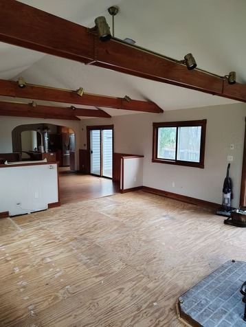 A living room with wooden beams on a vaulted ceiling.
