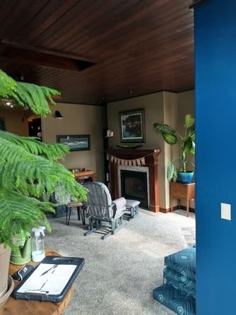 A cozy living room with a fireplace, a wood-paneled ceiling.