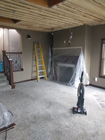 A room under renovation with carpet, a yellow stepladder, a vacuum cleaner.