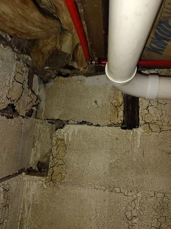 A close-up of a basement wall showing horizontal cracks in concrete blocks.