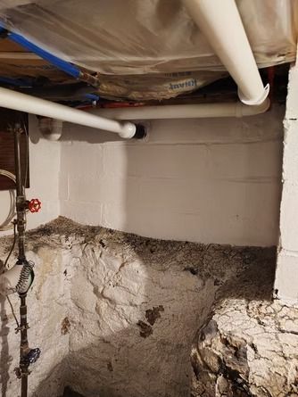 A basement corner showing painted white cinder blocks above an unfinished stone foundation.