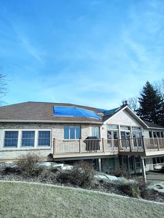 A house with a large blue tarp covering a section of the shingled roof.