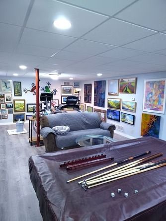 A basement game room featuring a pool table with cues, a gray sofa, exercise equipment.