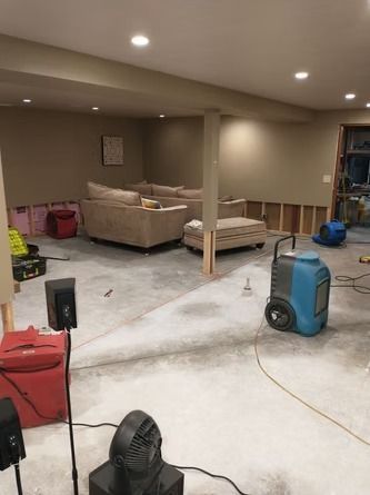 Basement undergoing water damage remediation with industrial dehumidifiers.