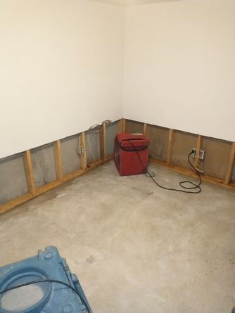 A room undergoing water damage restoration with removed drywall, exposed studs.
